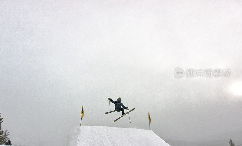 一名穿着全套冬季装备的滑雪者在科罗拉多州博尔德附近的埃尔多拉滑雪度假村滑雪道上尝试跳跃的“转换牛仔表演”把戏