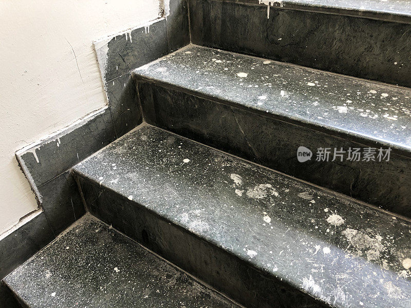 灰尘飞扬的灰色花岗岩楼梯的踏板和立管形象，台阶的特写覆盖着砖石油漆飞溅和飞溅，糟糕的家庭室内装饰概念
