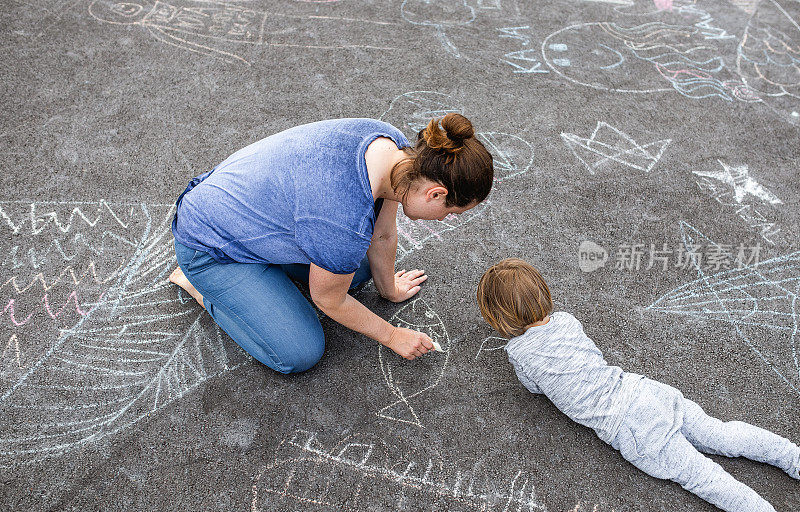 小男孩和他妈妈在柏油路上涂鸦