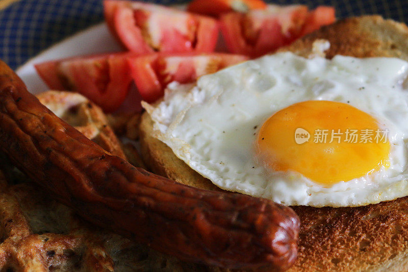 特写图像显示的元素全英国早餐油炸香肠，华夫饼，煎蛋，生番茄和白吐司在盘子上