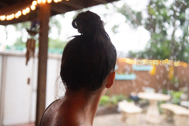 后脑勺年轻的西班牙妇女看热带风暴雨从天庭