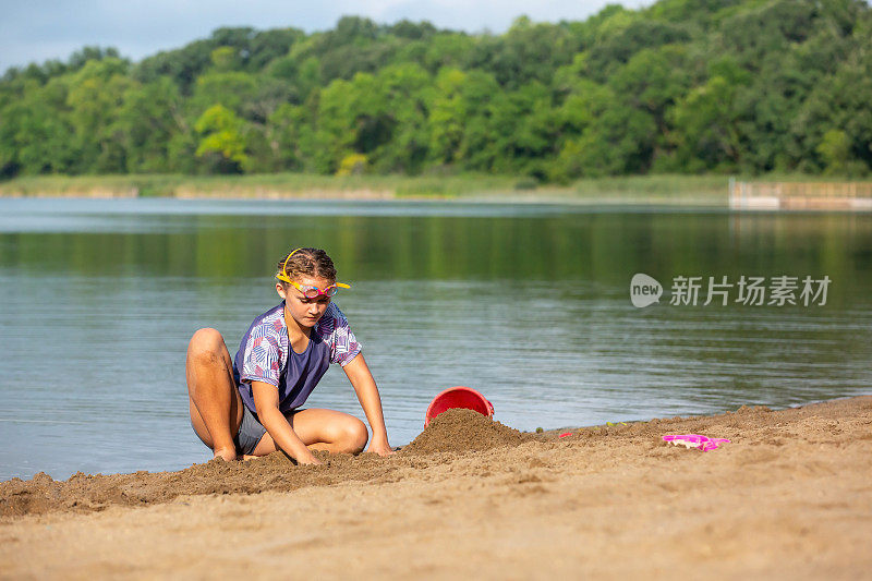 夏天，女孩在海滩边玩沙子