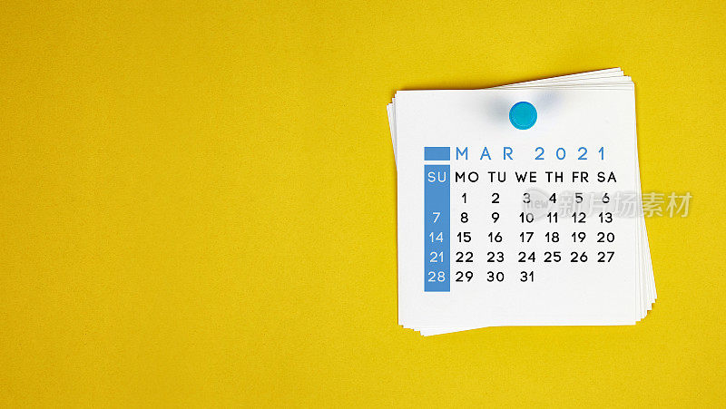 2021年3月的日历钉在黄色的背景上。