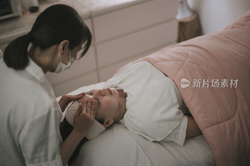 亚洲华人女性美容师清洁擦拭做面部治疗，为她的客户在面部美容沙龙