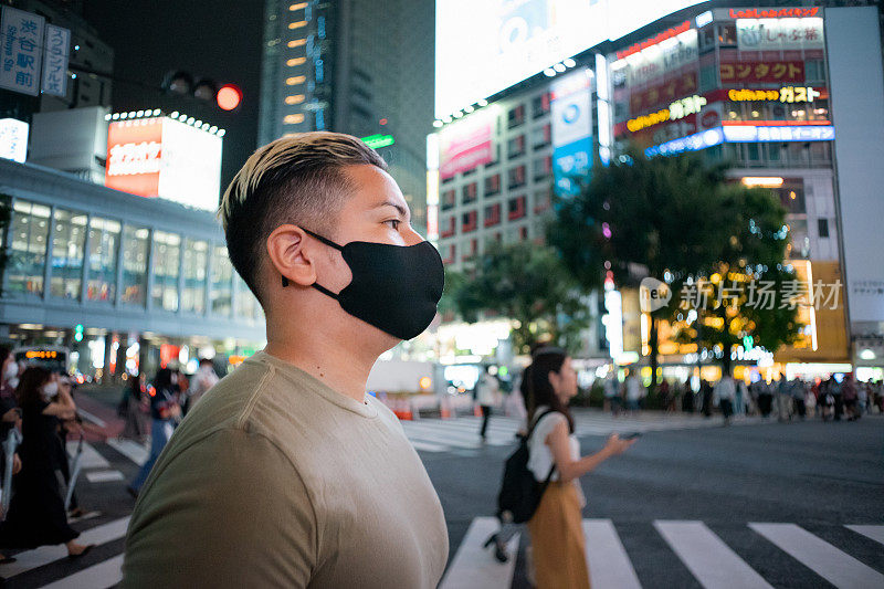 东京涩谷十字路口，一名年轻男子晚上戴着面具的肖像