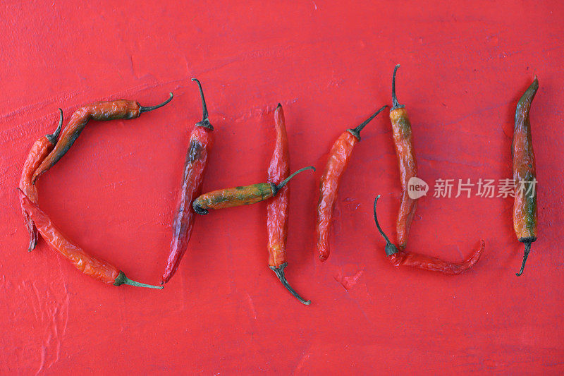 干辣椒、红辣椒和绿辣椒的图像在红色背景下形成单词chili