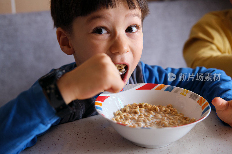 可爱的孩子们早餐吃玉米片和牛奶