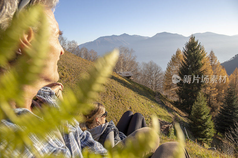 徒步旅行者早上在长满草的山坡上休息