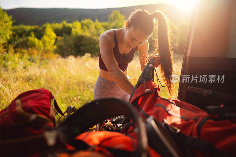 微笑的女人把登山装备装进背包