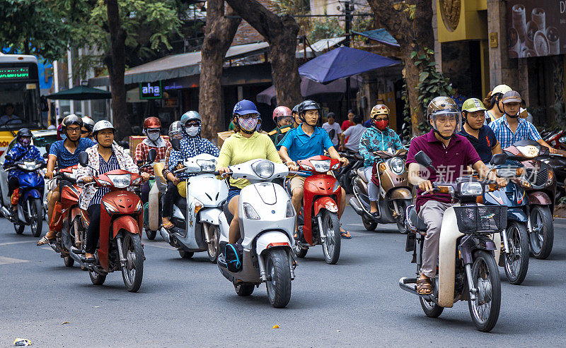 在越南河内的一条小路上，戴着面具的摩托车手。