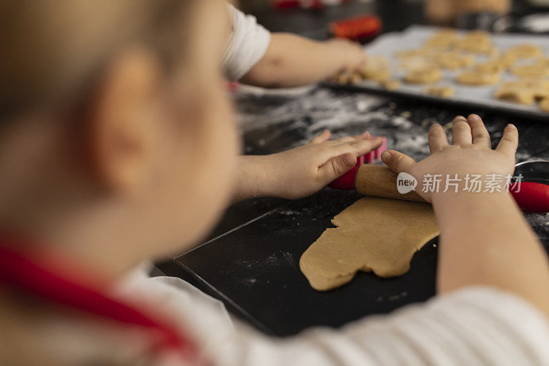 在小女孩正在擀饼干面团的肩膀上