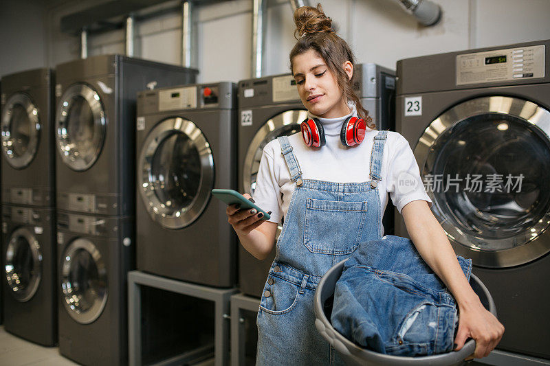 一个年轻的白人女人在自助洗衣店洗衣服
