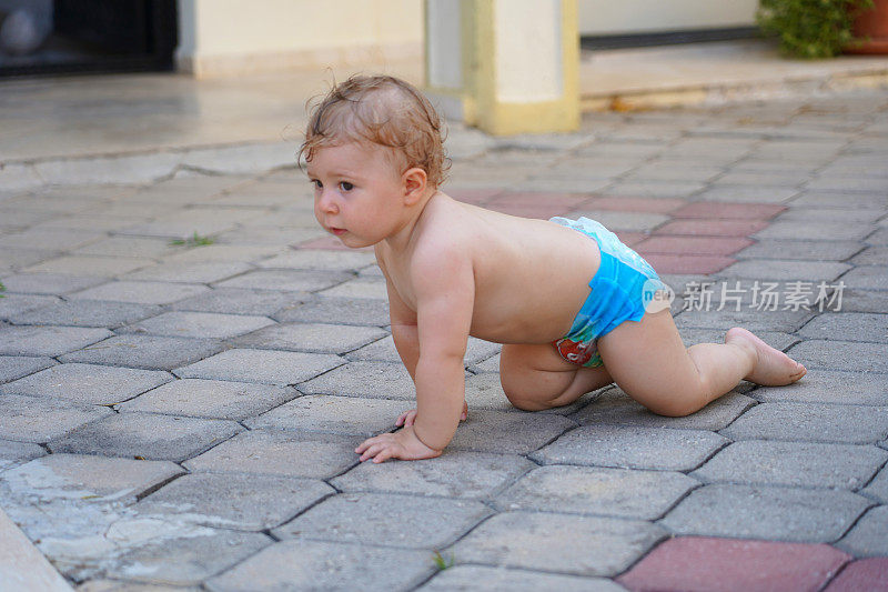 婴儿光着身子在泳池边爬，一岁的孩子