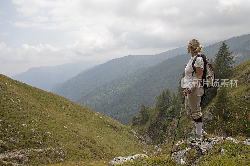 一名女性徒步旅行者在山谷上方的一个小丘上休息