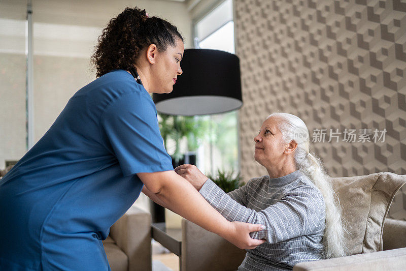 家庭护理人员帮助一位年长妇女站在家里