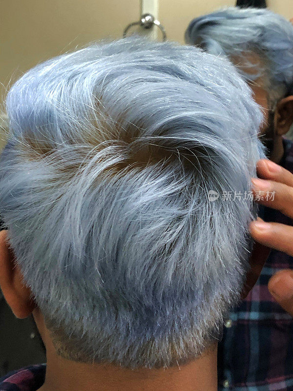 特写图片:一名印度男子在发廊里梳着新发型，黑色的头发被染成了金色，并被化学物质染成了蓝色和灰色