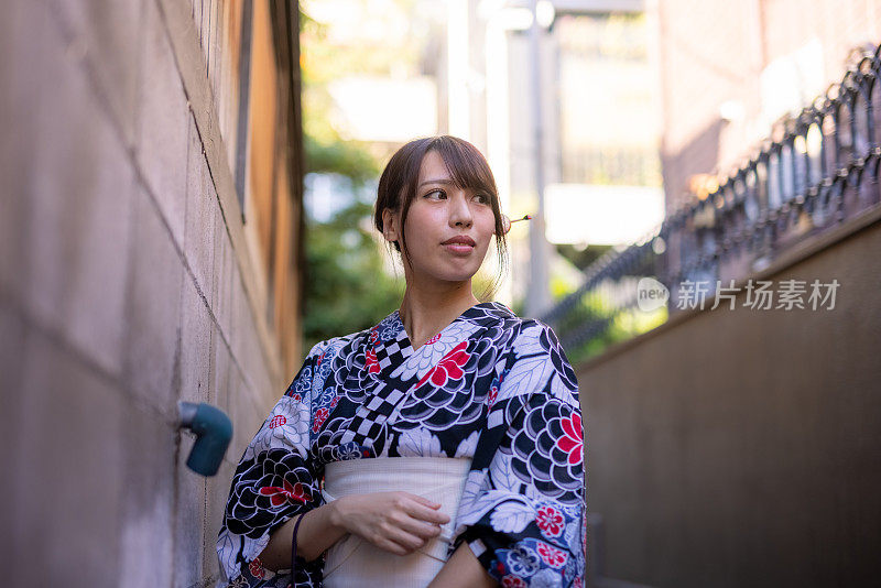 一位日本妇女走在一条狭窄的人行道上