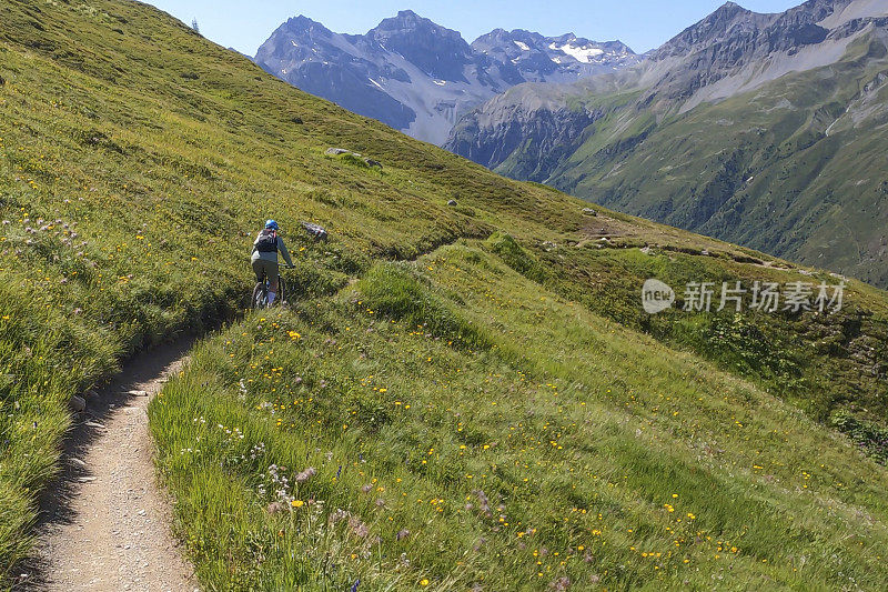 女人沿着阳光明媚的自行车道骑山地车