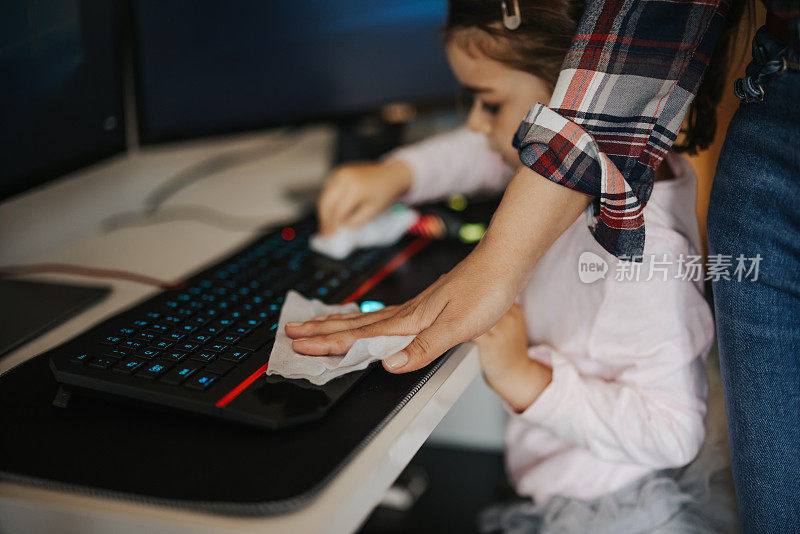 母亲和小女儿正在给电脑键盘消毒