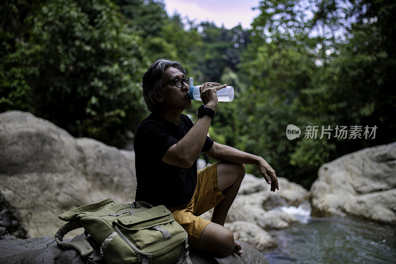 肖像高级成人在丛林徒步旅行期间喝淡水