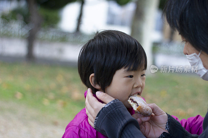 母亲在户外给她的小女儿分发面包