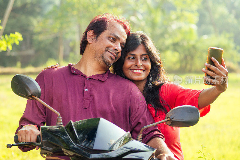 幸福的印度夫妇骑着摩托车在印度果阿的热带丛林里