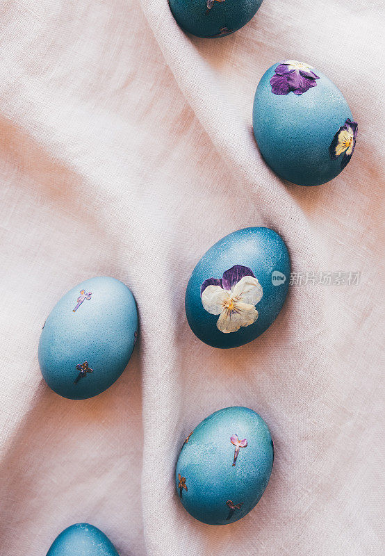 自然染色的青蓝压花复活节蛋在中性米色桌布背景。俯视图，平躺风格。手工工艺，天然装饰。