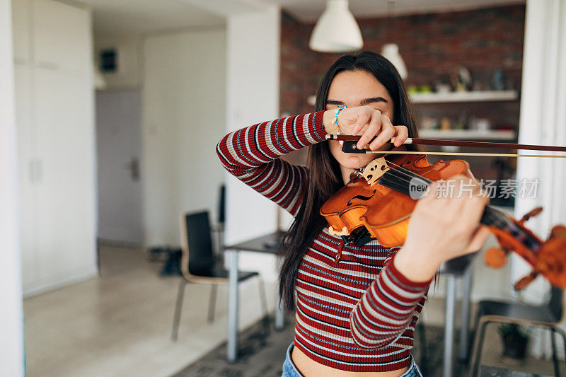 一位不知名的女小提琴家正在家里练习拉小提琴。