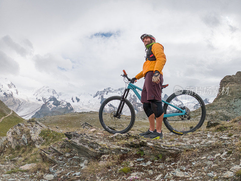 男性山地自行车爱好者欣赏风景，土路，远处的冰川