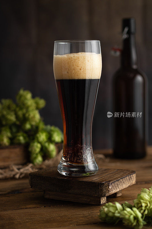 啤酒。一大杯啤酒，有泡沫，啤酒花放在旧木板上。啤酒的概念。Oktoborfest。古董。