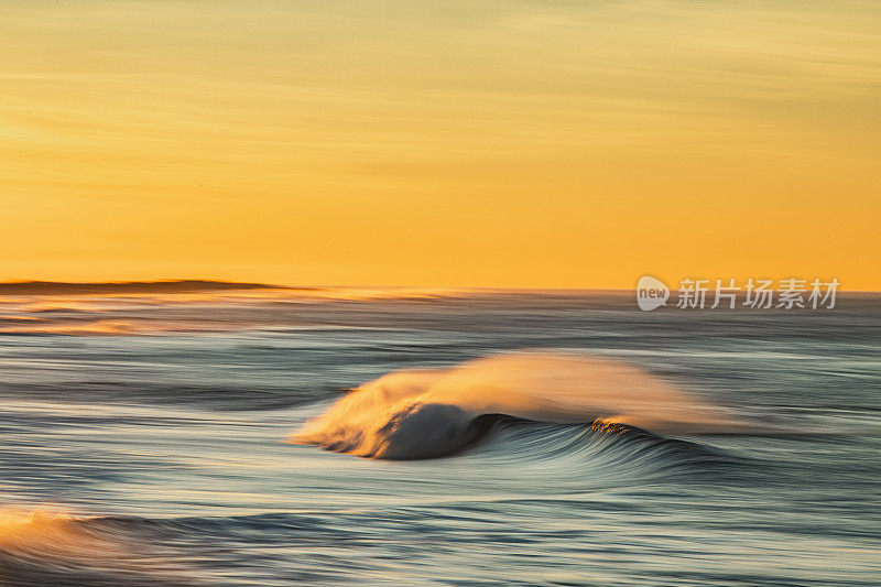 金色的海浪在沙滩上反射出明亮的金色日出