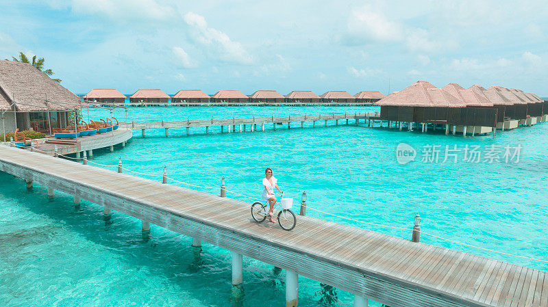 马尔代夫木制码头上骑自行车的年轻女子