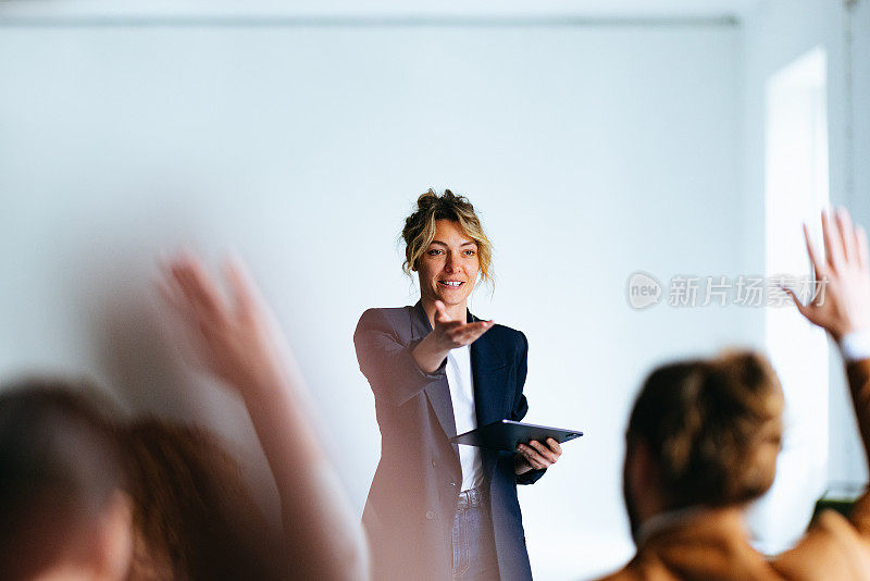 微笑的女商务人士在问答环节中指着观众说话