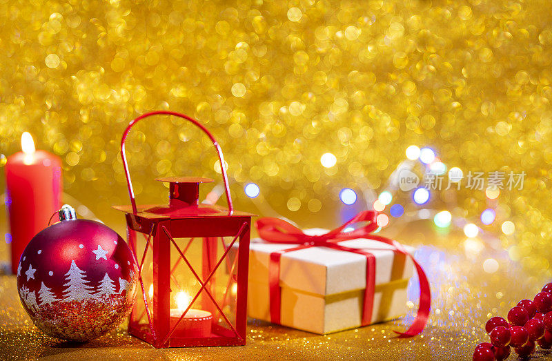 红色的蜡烛灯笼和礼品盒，金色的闪光圣诞背景和红色的小彩灯
