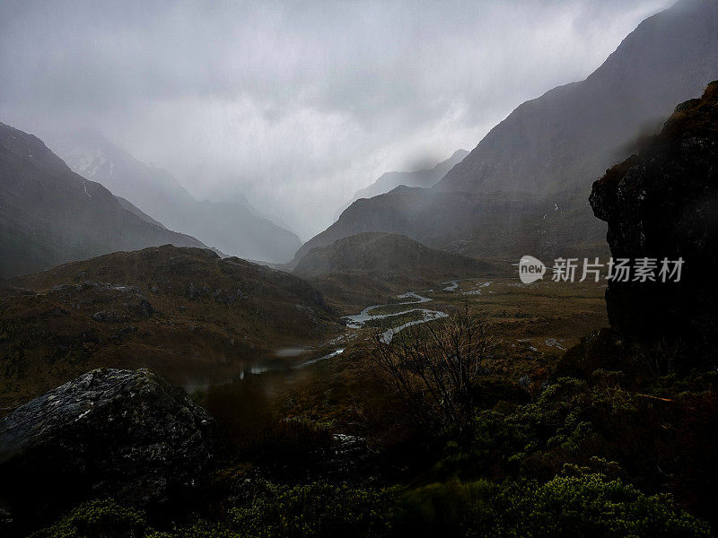 在大雨中，从高处俯瞰充满乌云的黑暗山谷，路特本瀑布小屋。路本赛道，阿斯帕山国家公园，新西兰。