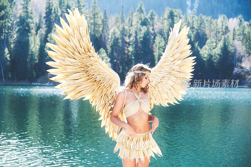 装扮成天使的女孩出现在湖的背景上