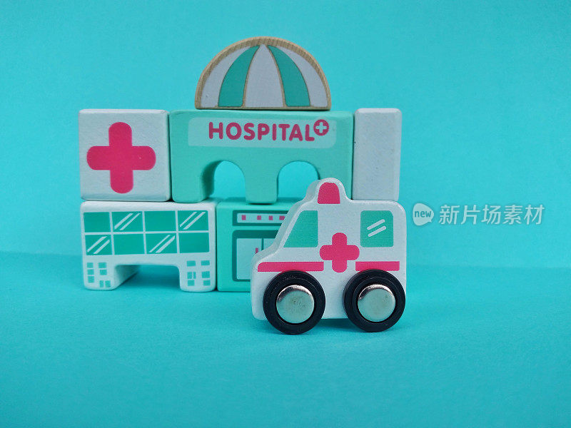 医院大楼和木制积木制成的玩具救护车。医疗保健药学概念