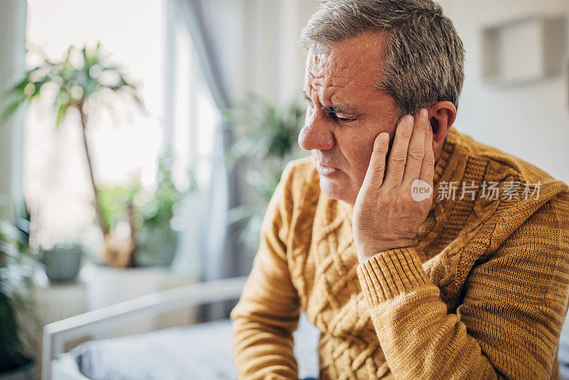 一个男人用手捂住他生病的耳朵