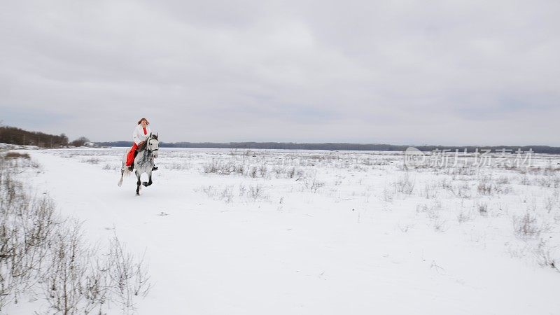 身穿红裙的女骑师骑在疾驰的骏马上，在冬天的雪地里