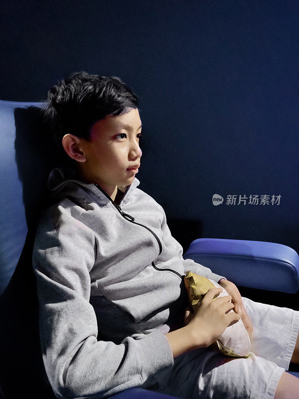 亚洲男孩正在电影院看电影。