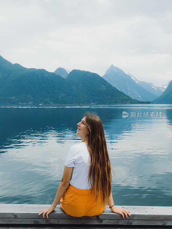 挪威一名妇女凝视峡湾景色的后视图