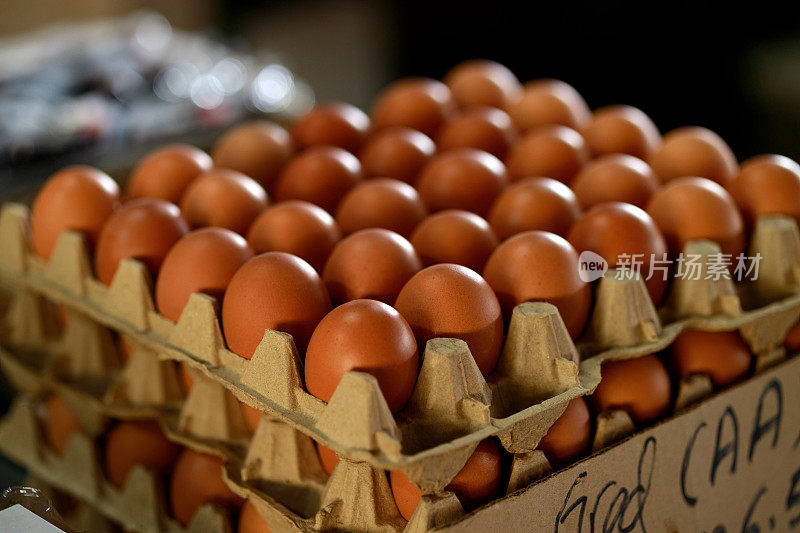 AA级新鲜鸡蛋精心排列并堆放在纸箱里，可在农贸市场出售。