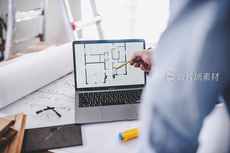 建筑师在笔记本电脑屏幕上检查房屋平面图