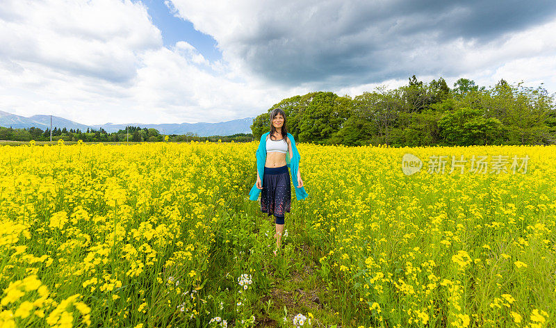 一位妇女在一片黄色的油菜花地里放松和享受户外活动