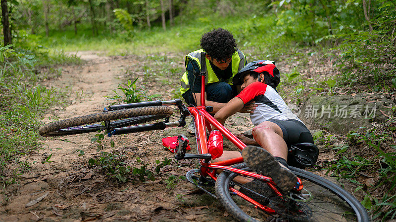 MTB山地车事故及急救:自行车手碰撞事故，膝盖和腿部受伤，急救帮助山地车在事故中。山地车运动员急救队在比赛事故中受伤。
