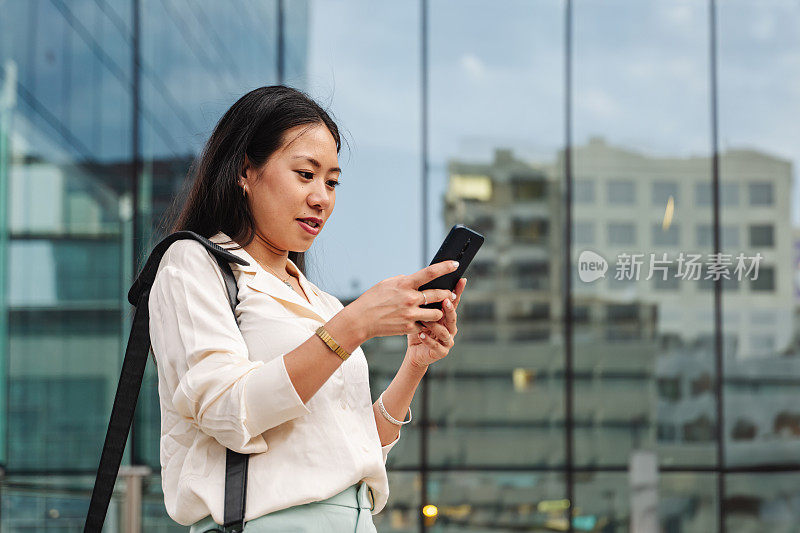 年轻优雅的亚洲商务女性在城市户外使用手机