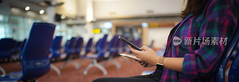 在机场等待起飞的女性在您的假期中持有护照和智能手机，而在机场候机区等待登机