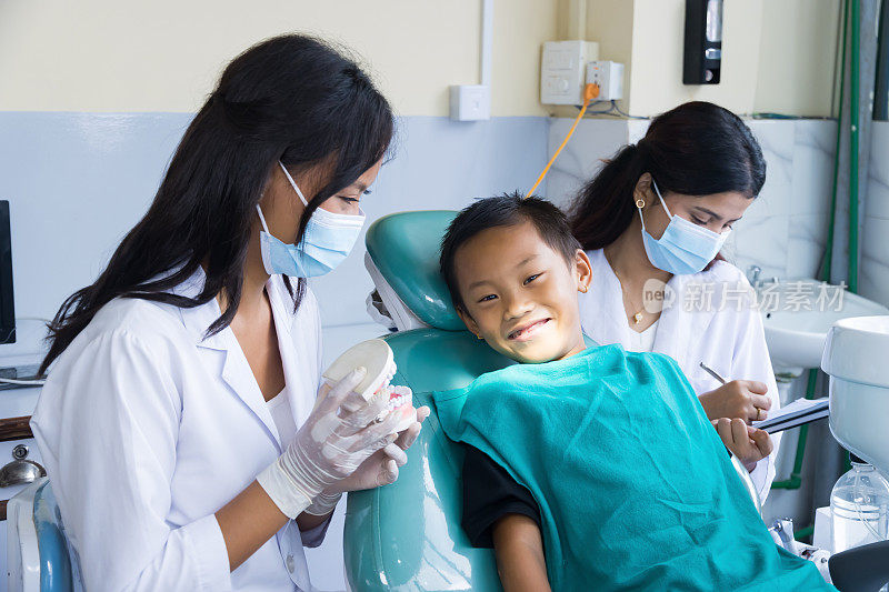 快乐的孩子在牙医诊所与女护士和医生