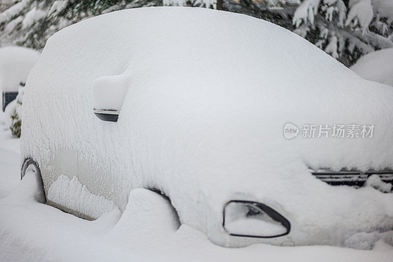 被大雪困住的汽车一动不动地停在房子院子里的雪地里