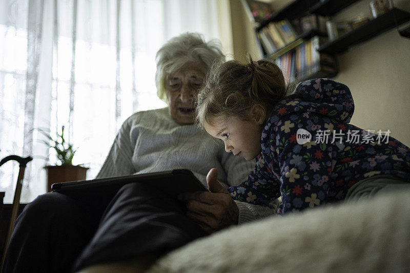 曾祖母给小女孩读电子故事。